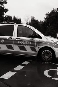Vertical grayscale of two officers in a German police car on a rainy day in Dusseldorf