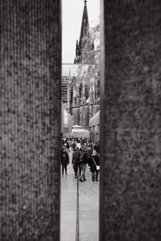 Greyscale shot of the Cologne Cathedral between two stone columns in Cologne, Germany
