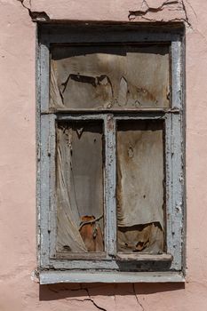 old wooden window in cracked wall with dirty rag inside.