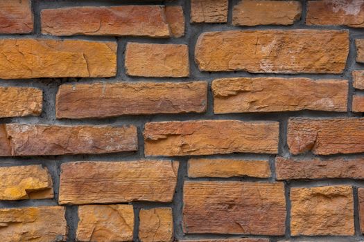 flat close-up full frame background and texture of decorative orange stone bricks.