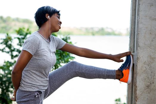 Sport and recreation.Small woman in gray sportswear stretching outdoors.