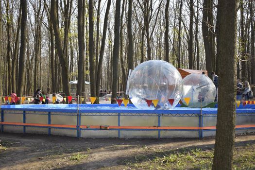 Zorbing in the pool. Little children in an inflatable balloon, having fun on the water. The ball in the water - fascinating summer attractions for children. Water zorbing