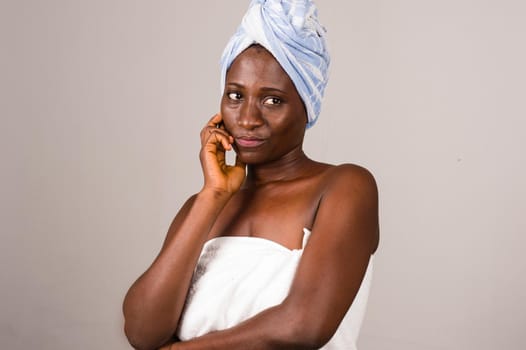 young woman standing on gray background napkin tied on head angry and looks at the camera.