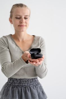 Wireless technology. Young woman holding wireless earbuds