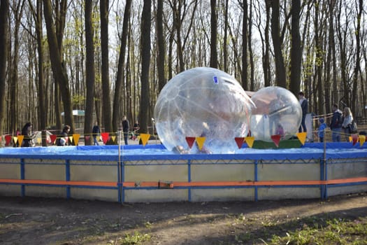 Zorbing in the pool. Little children in an inflatable balloon, having fun on the water. The ball in the water - fascinating summer attractions for children. Water zorbing