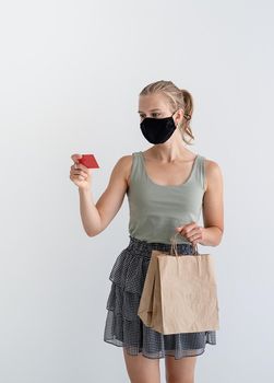 Online shopping concept. woman in protective mask holding eco friendly shopping bags and credit card