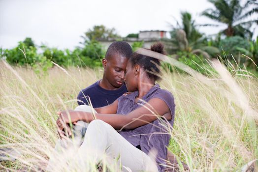 happy young couple in love relaxes sitting in the grass in summer. Positive man and a woman having fun enjoying the outdoors and vacation.