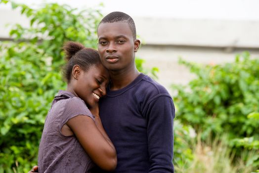 young african couple standing in park, intertwined.