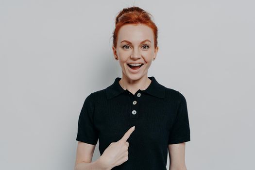 Young excited overjoyed ginger female being mentioned or being choosen by someone, pointing at herself with forefinger and staring at camera with amazed face expression and dropped jaw