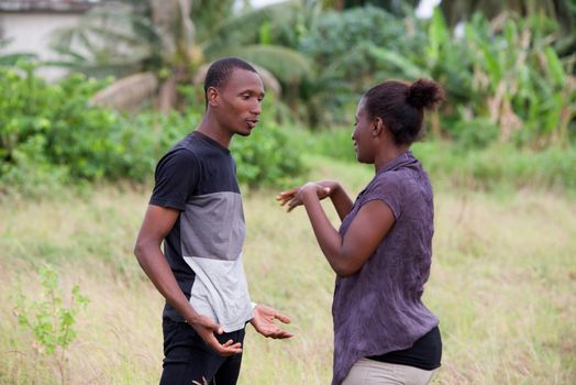 young couple in love standing and talking at the park in the grass during the day
