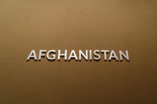 the word afghanistan laid with silver metal letters on rough flat tan khaki canvas fabric surface
