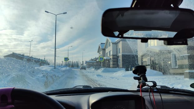 Looking throught car window to the city, town or village street with houses buildings in winter or spring time