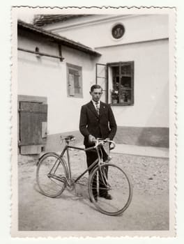 THE CZECHOSLOVAK REPUBLIC - CIRCA 1940s: Vintage photo of a young man with bicyckle on the back yard.