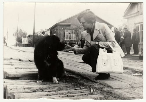 USSR - CIRCA 1970s: Vintage photo shows woman strokes the dog on the street.