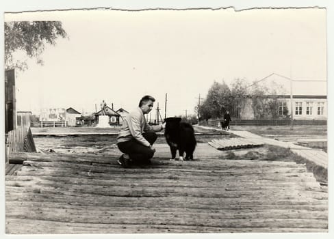 USSR - CIRCA 1970s: Vintage photo shows man strokes the dog on the street.