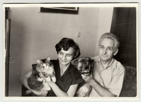 USSR - CIRCA 1980s: Vintage photo shows woman cradles cat and man holds dog.