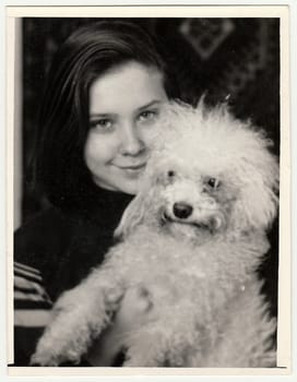 USSR - CIRCA 1980s: Vintage photo shows young woman cradles dog (poodle).