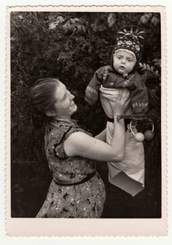 USSR - CIRCA 1970s: Vintage photo shows mother holds toddler with rattle.