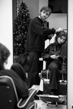 Beautiful young woman in modern hair salon. hairdresser checking hairstyle of caucasian girl