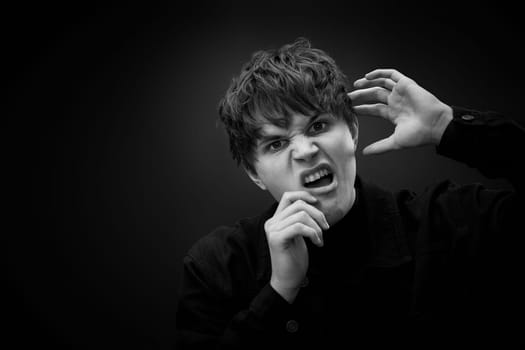 portrait of crazy young man with awesome hairdo grimacing and yelling with a violent or desperate face. black and white