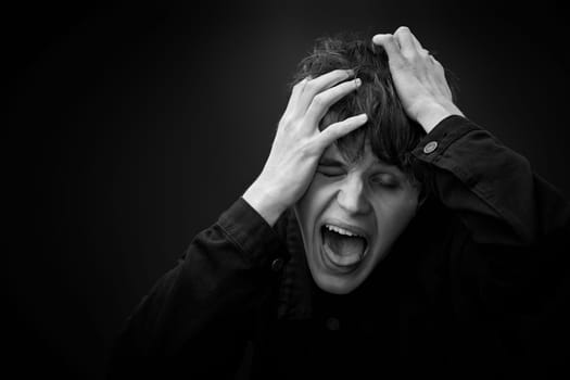 portrait of crazy young man yelling with a violent or desperate face and grimacing . black and white