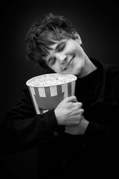 portrait of crazy young man holding bucket of popcorn and grimacing . black and white