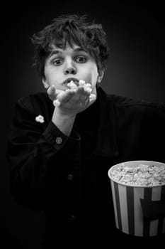 portrait of crazy young man throwing up popcorn and grimacing . black and white