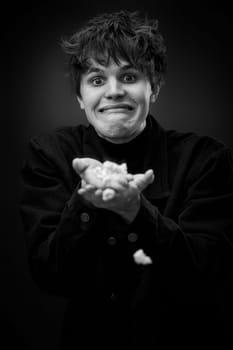 portrait of crazy young man throwing up popcorn and grimacing . black and white