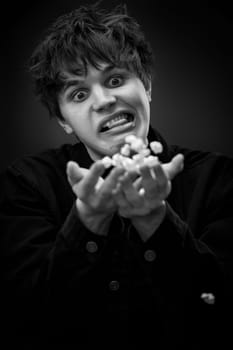 portrait of crazy young man throwing up popcorn and grimacing . black and white