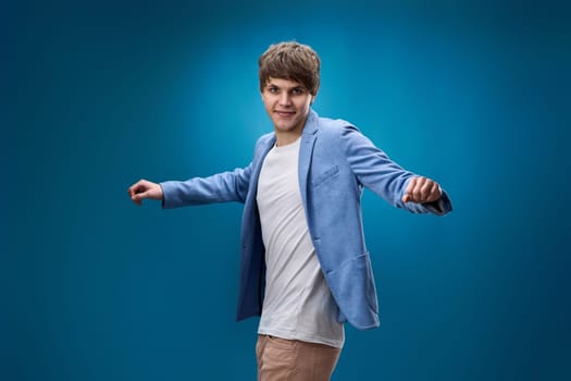 positive happy caucasian man in yellow sweatshirt dancing on blue background