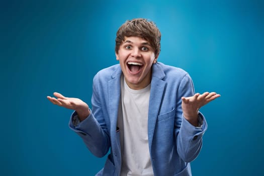 happy shocked man with surprise expression and excited face on blue studio background