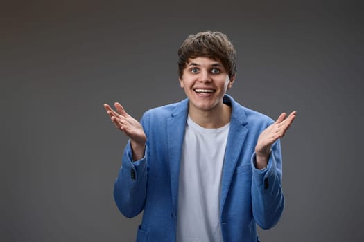 happy shocked man with surprise expression and excited face in blue jacket on gray studio background