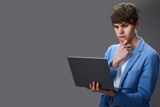 caucasian young freelancer man using laptop computer for online work isolated on gray background