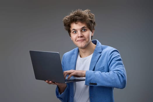 Funny and crazy caucasian man with laptop on gray background