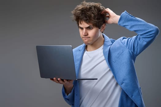 Funny and crazy caucasian man with laptop on gray background