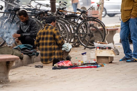 Chandigarh, India - circa 2023 : street side cobbler sitting on road and mending shoes in the winter months in sector 17 chandigarh during morning showing how the poor earn a living