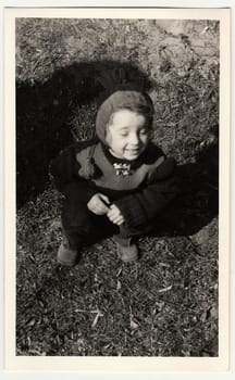 THE CZECHOSLOVAK REPUBLIC - CIRCA 1940s: Retro photo shows girl sits on grass.