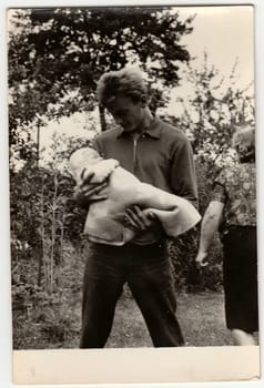 THE CZECHOSLOVAK SOCIALIST REPUBLIC - CIRCA 1960s: Vintage photo shows young man cradles baby.