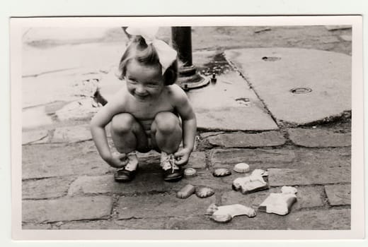 THE CZECHOSLOVAK REPUBLIC - CIRCA 1940s: Retro photo shows girl plays with retro sand toys in the back yard.