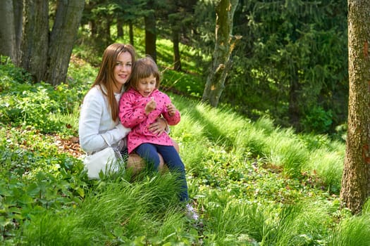 a woman in relation to her child or childrenPretty mother with a cute child walk in the forest park studying nature.