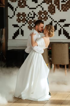 the first dance of the bride and groom inside a restaurant with heavy smoke