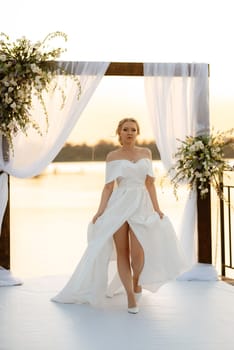 bride against the background of a yellow sunset on a pier near the river