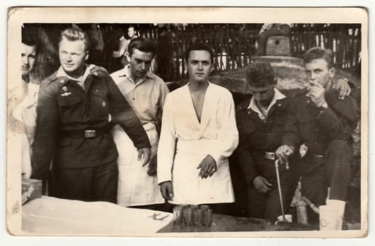 THE CZECHOSLOVAK SOCIALIST REPUBLIC - CIRCA 1960s: An antique Black & White photo shows soldiers during the outside party. Vintage photo shows beer tap too.