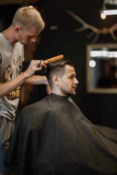 portrait of a young guy groom at the training camp in the barbershop with shaving and styling