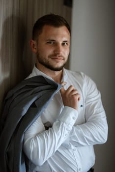 portrait of smiling groom with beard in blue color suit