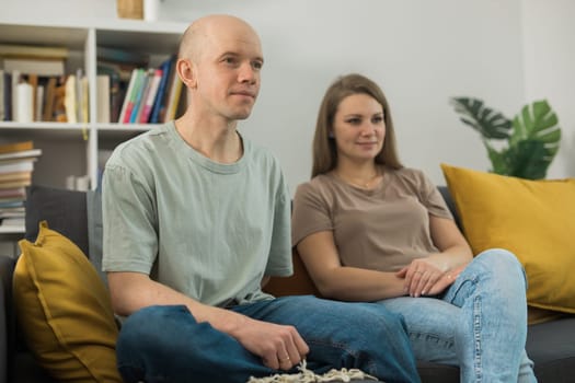 Young couple relaxing and watching TV at home, they focus on a dramatic moment in a film - streaming service and free time