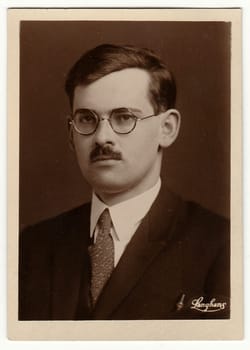 THE CZECHOSLOVAK REPUBLIC - CIRCA 1920s: Vintage photo shows young man with glasses and moustache. Antique black white photo with sepia tint