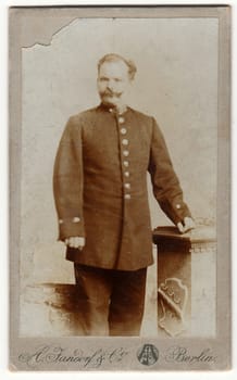 BERLIN, GERMANY - CIRCA 1895: Vintage cabinet card shows man wears a postman uniform. Antique black white photo.