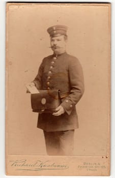 BERLIN, GERMANY - CIRCA 1895: Vintage cabinet card shows man wears a postman uniform. Antique black white photo.