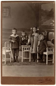 HODONIN, AUSTRIA-HUNGARY - CIRCA 1910: Vintage cabin card shows a group of children. Antique black white photo was taken in studio.